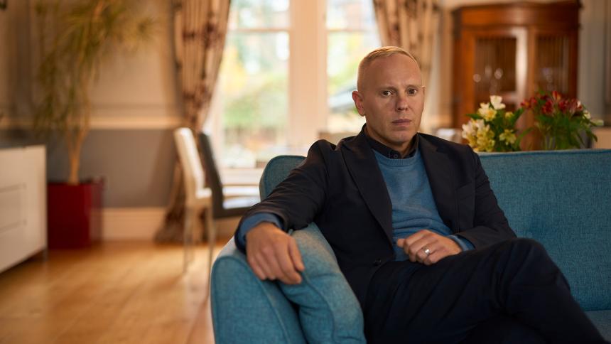 Rob Rinder sitting on a sofa