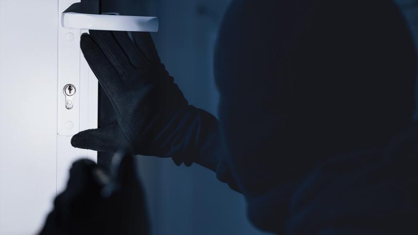A man looks to pick the lock of a front door