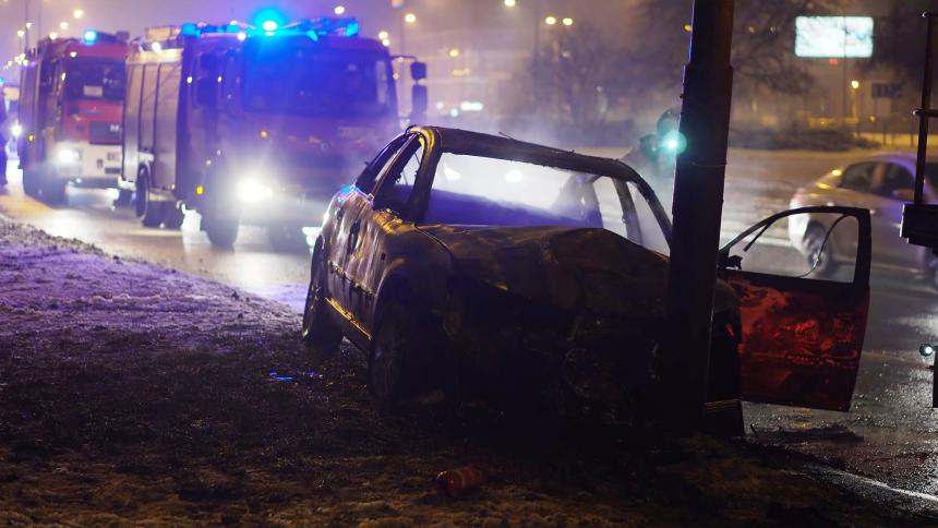 A car crashed into a post with fire engines in the background