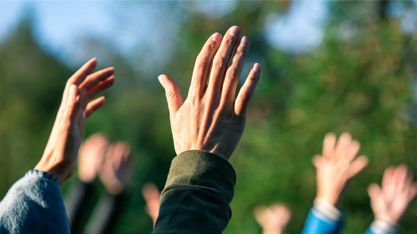 A group of people standing outside with their hands in the air